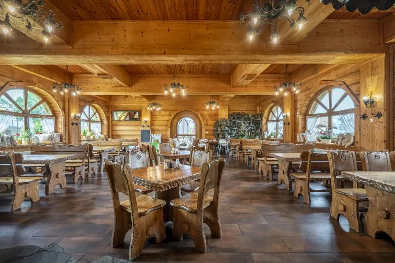 Sala restauracji w drewnie — rzeźbione krzesła, ciepłe światło żyrandoli