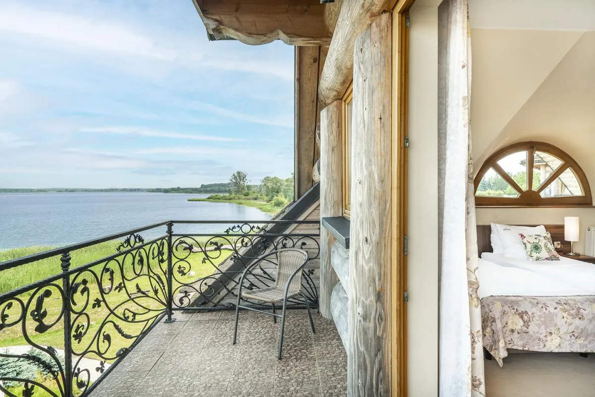 Balkon pokoju COMFORT z kutą balustradą i stolikiem, widok na jezioro i trzcinowisko